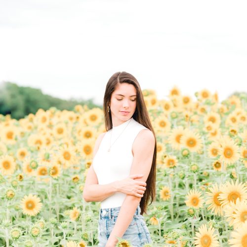 Woman standing among the sunflowers during her sunflower mini session at Dogwood Farms in Belews Creek NC